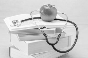 Stack of medical books, stethoscope and apple